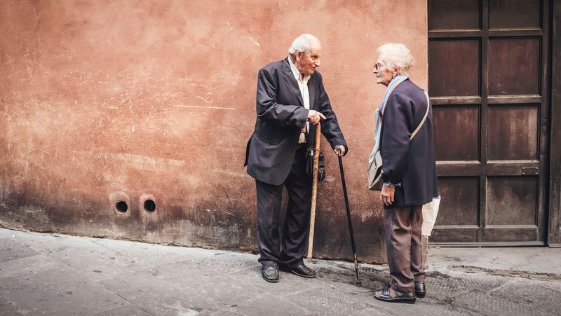 Dos vecinos mayores pasean con bastón por su calle