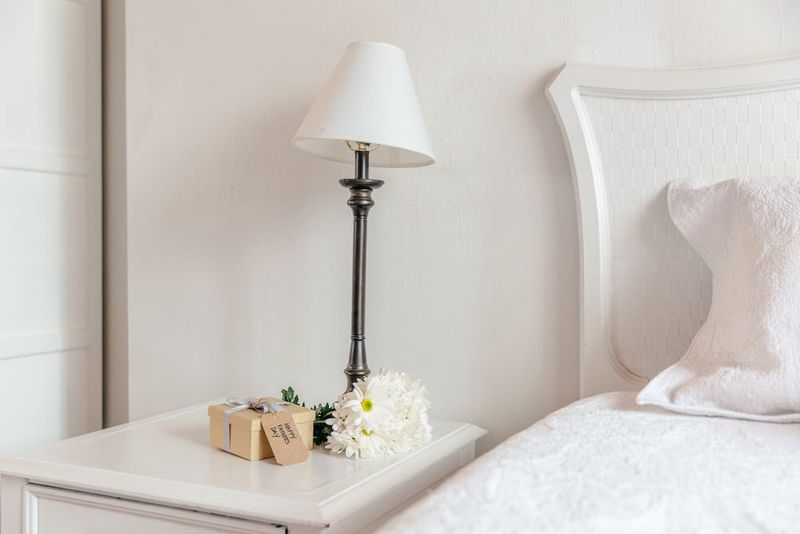Dormitorio clásico con cabecero blanco y una lámpara sobre la mesilla de noche